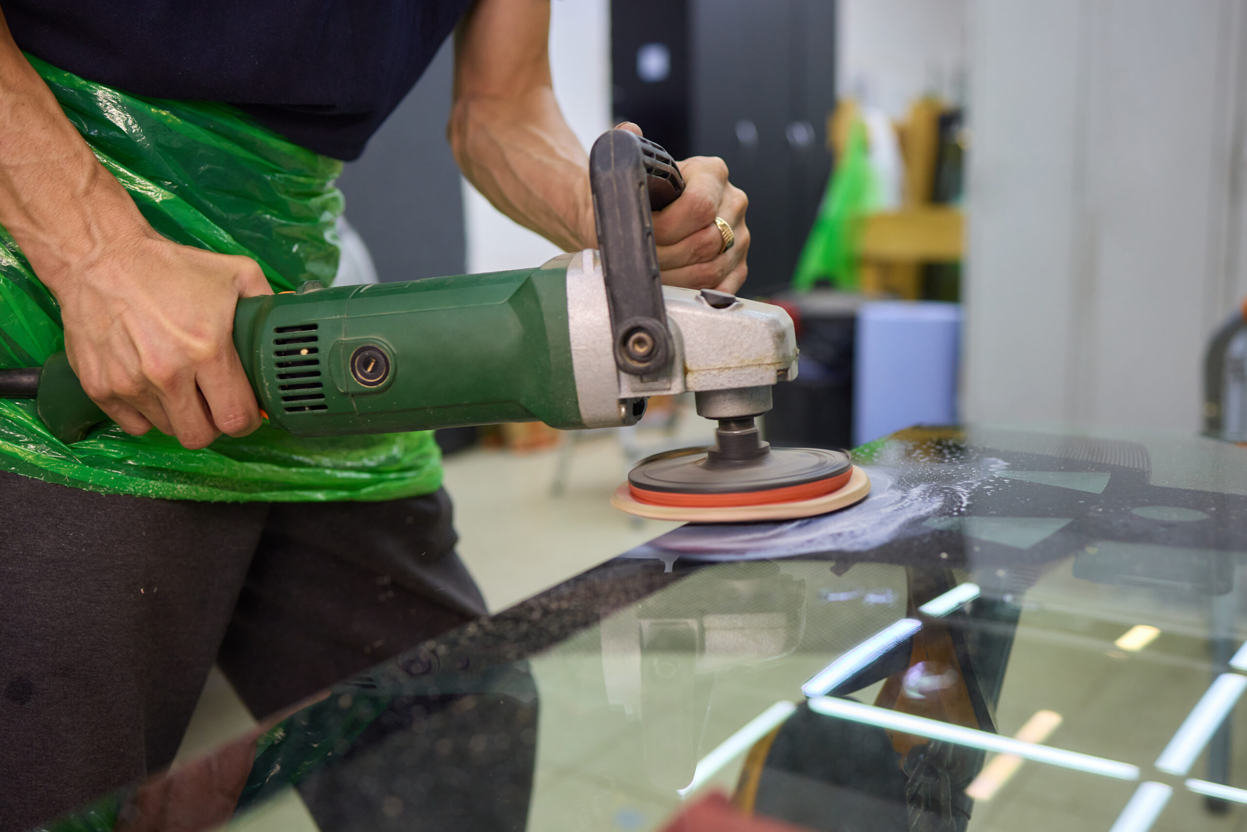 A technician uses a polishing machine to polish a glass surface, showcasing detailed technical craftsmanship