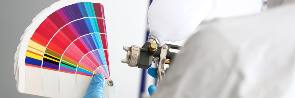 Hands of workman holding spray gun and colorful fantail picking ral colour to paint closeup